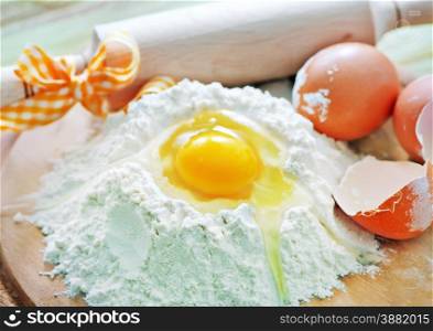 flour and raw eggs on the wooden board