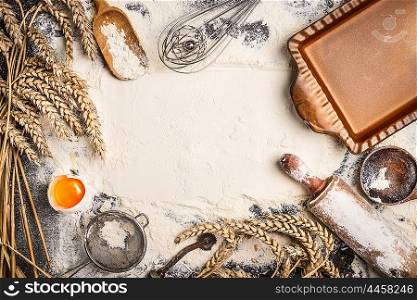 flour baking background with raw egg, rolling pin, wheat ear and rustic bake pan. Top view