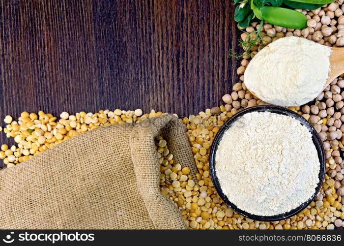 Flour chickpeas in a bowl and of pea in a spoon, green pods on burlap background on wooden board