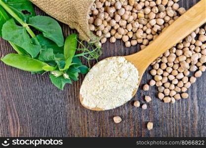 Flour chickpeas in spoonful, chick-peas in a sack and fresh pea pods on a background of wooden boards top
