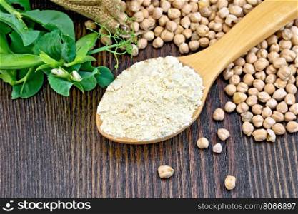 Flour chickpeas in spoonful, chick-peas in a sack and fresh pea pods on a background of wooden boards