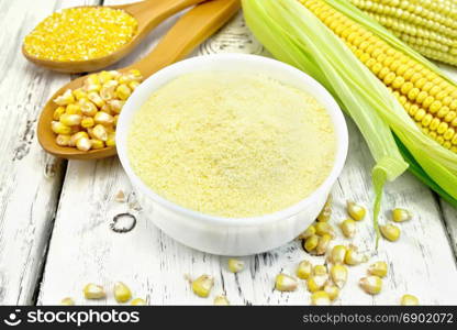 Flour corn in a bowl, groats and grain maize in the spoons, cobs on the background of wooden boards
