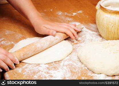 Flour in capacity with dough and rolling pin on the wooden table