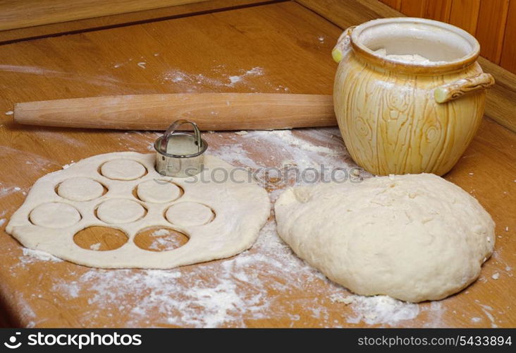 Flour in capacity with dough and rolling pin on the wooden table
