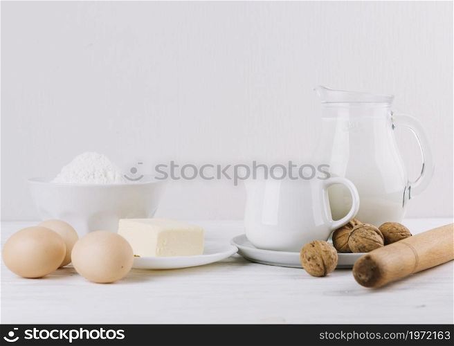 flour milk eggs cheese rolling pin walnuts white backdrop making pie. High resolution photo. flour milk eggs cheese rolling pin walnuts white backdrop making pie. High quality photo