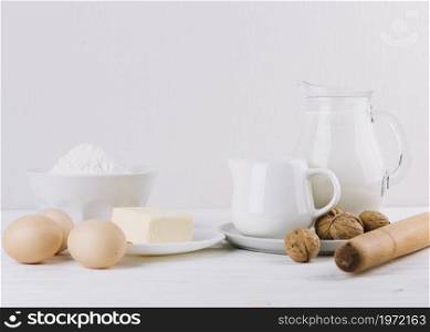 flour milk eggs cheese rolling pin walnuts white backdrop making pie. High resolution photo. flour milk eggs cheese rolling pin walnuts white backdrop making pie. High quality photo