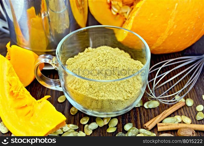 Flour pumpkin in a glass cup, sieve, mixer and cinnamon, cloves fresh pumpkin, pumpkin seeds on the background of wooden boards
