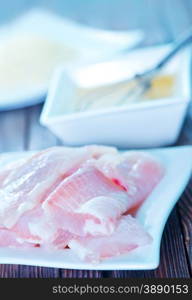 flour, raw egg and raw fish on a table