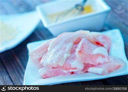 flour, raw egg and raw fish on a table