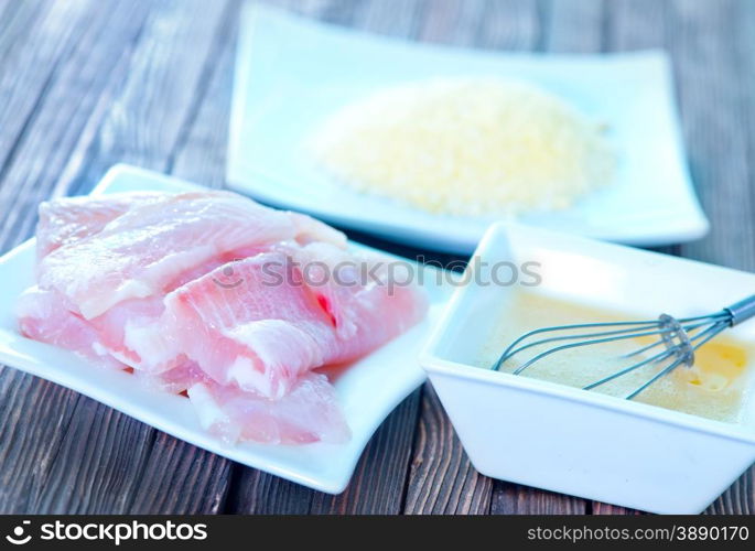 flour, raw egg and raw fish on a table