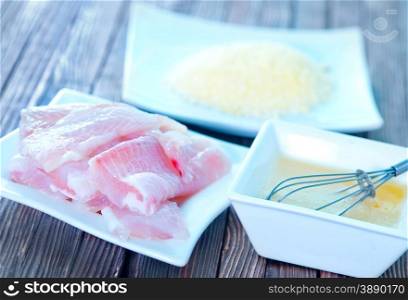 flour, raw egg and raw fish on a table