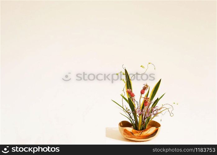 Flower arrangement in wooden vase on empty wall background with copy space.