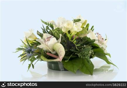 flower arrangement with lilys freesia and arum on soft blue background