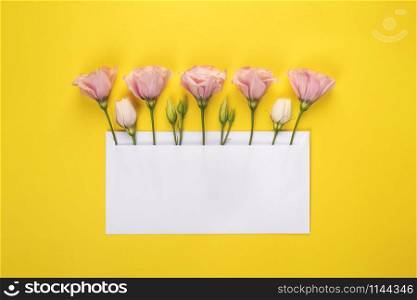 Flower banner with copy space. Pink Eustoma flowers arrangement with blank card on yellow background. Top view. Flower banner with copy space. Pink Eustoma flowers arrangement with blank card on yellow background.