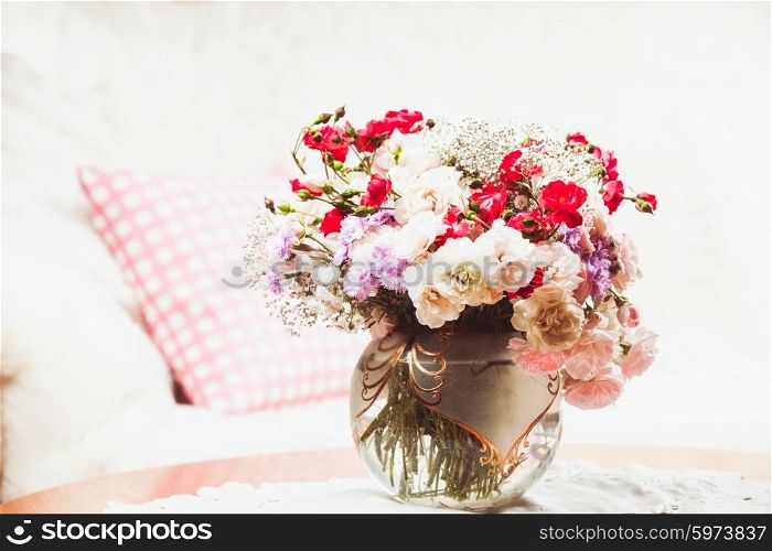 Flower bouquet on the table near the sofa with a pillow. Flower bouquet on the table