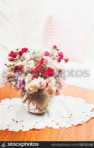 Flower bouquet on the table near the sofa with a pillow. Flower bouquet on the table