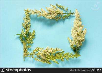 Flower composition. Frame nature floral rectangular wreath of blooming twig white flowers on blue background. Flat lay Top view. Mock up Template for postcard, lettering text or your design.. Flower composition. Frame nature floral rectangular wreath of blooming twig white flowers on blue background. Flat lay Top view. Mock up Template for postcard, lettering text or your design
