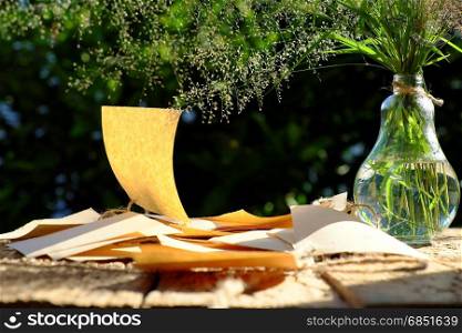 Flower grass in glass jar with note paper in wind blow at evening sun make feeling and calm, wild tiny flowers on green natural background in garden