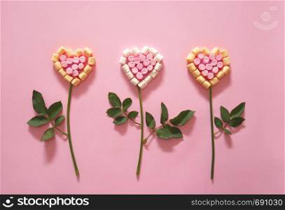 Flower in shape of a heart made of mini marshmallows on pink background. Love concept