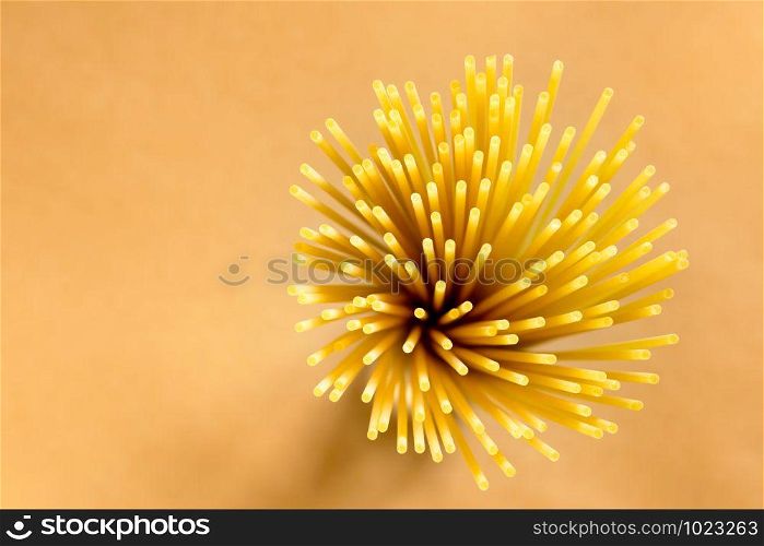 Flower of Italian spaghetti extruded through bronze, seen from the top on brown background