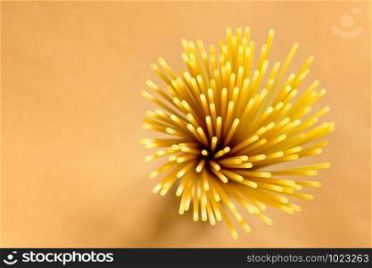 Flower of Italian spaghetti extruded through bronze, seen from the top on brown background