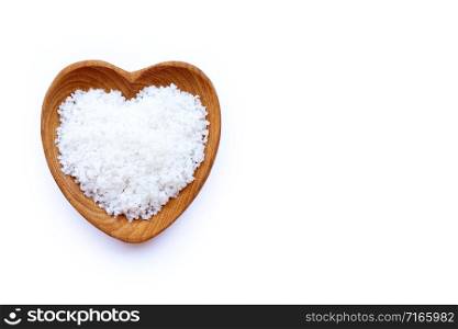 Flower of salt in heart shaped wooden bowl on white background.