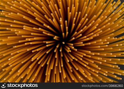 Flower of whole wheat spaghetti gathered in a bunch, view from top on stone plate