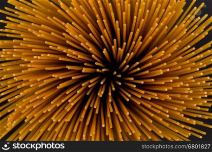Flower of whole wheat spaghetti gathered in a bunch, view from top on stone plate