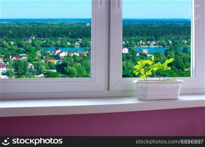 flower-pot on the window-sill and view to the country houses. flower-pot on the window-sill of cozy room and view to the country houses