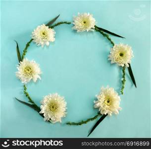 Flower round frame wreath made of white flowers on blue background. Flat lay, top view
