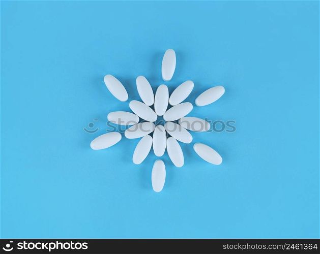 Flower shape made from white tablets on a blue backdrop.. Flower shape made from white tablets on blue backdrop.