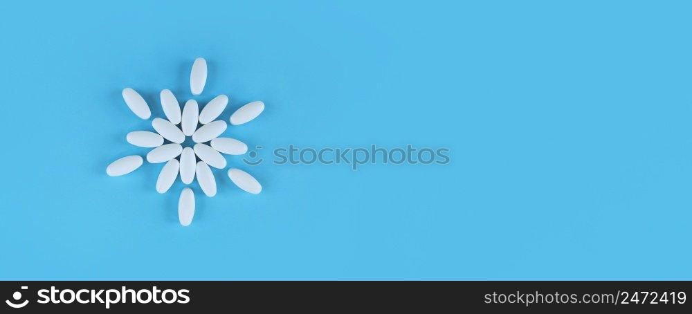 Flower shape made from white tablets on a blue backdrop with copy space.. Flower shape made from white tablets on blue backdrop with copy space.