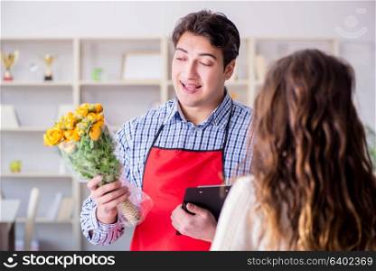 Flower shop assistant selling flowers to female customer