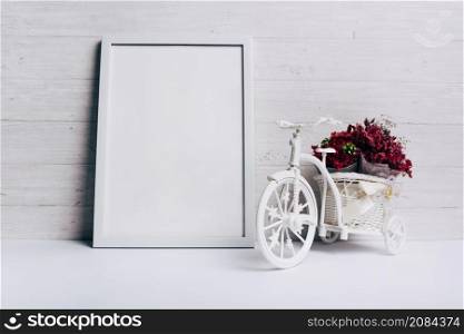 flower vase with bicycle near white blank frame desk