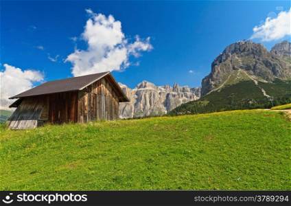 flowered meadow with a small barn beneath Dolomites mountains, Trentino, Italy