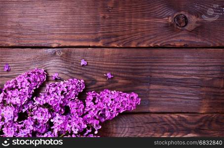 Flowering lilac branch on a brown wooden surface, empty space on the right