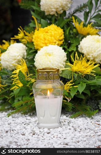 Flowers and votive candle which glows on the grave, lantern