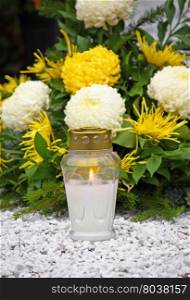 Flowers and votive candle which glows on the grave, lantern