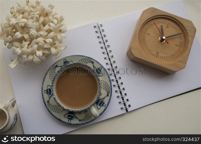 Flowers, coffee and notebooks and watches On a white wooden table that looks relaxed