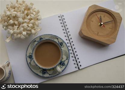 Flowers, coffee and notebooks and watches On a white wooden table that looks relaxed