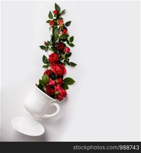 Flowers composition. Creative layout made of coffee or tea cup with red roses on white background