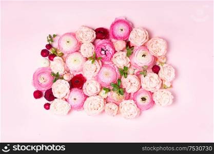 Flowers composition. Pattern made of roses and ranunculus flowers on pink plain background. Flat lay, top view backdrop. Flowers flat lay composition