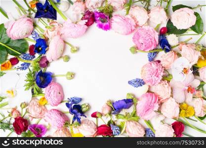 Flowers composition. Round frame made of roses, ranunculus and orchids flowers on white background. Flat lay, top view scene with copy space. Ranunculus flat lay composition
