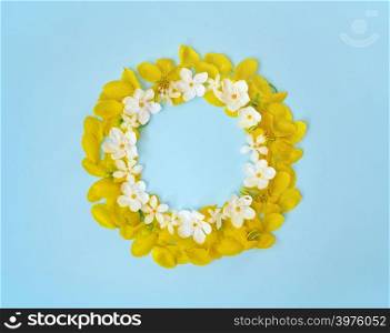 Flowers composition. Wreath made of yellow and white flowers on light blue background.