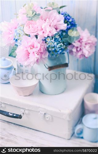 Flowers in a blue vintage can on white retro bag and kitchen earthenware