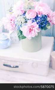 Flowers in a blue vintage can on white retro bag and kitchen earthenware