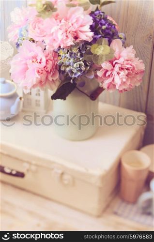 Flowers in a blue vintage can on white retro bag and kitchen earthenware. Vintage still life