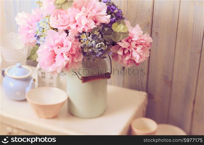 Flowers in a blue vintage can on white retro bag and kitchen earthenware. Vintage still life