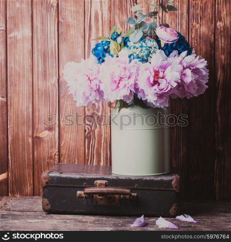 Flowers in a green vintage can and retro suitcases. Vintage still life