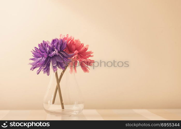 flowers in a vase on wooden table over white wall